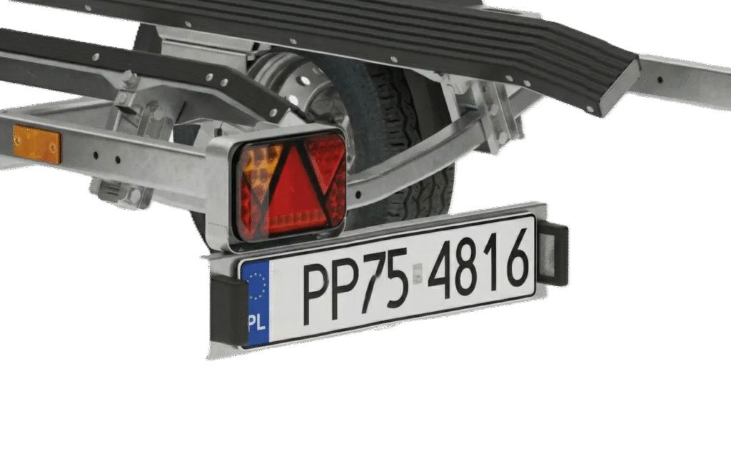Primer plano de la parte trasera de un remolque PP75-4816 P/O con matrícula PP75 4816 con banda azul UE PL, reflector triangular rojo, luz de freno y rueda.